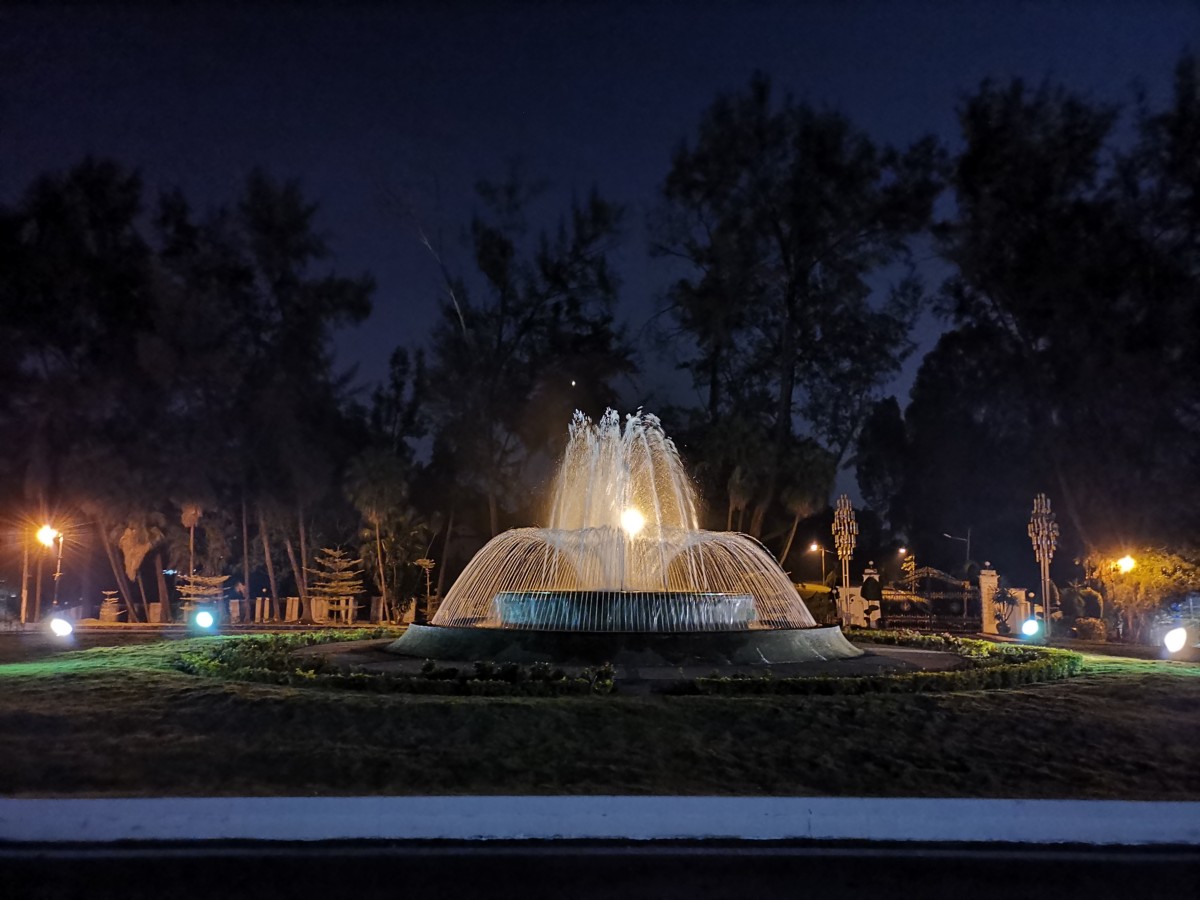 The HONOR View20 using Night mode on a fountain after dusk. The distant light sources give it a fairy light-like ambiance.